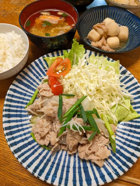 中央 ねぎ塩豚焼き肉とキャベツの千切り、左上白飯、中央上 甘海老のお吸い物、右上 里芋の煮物の画像